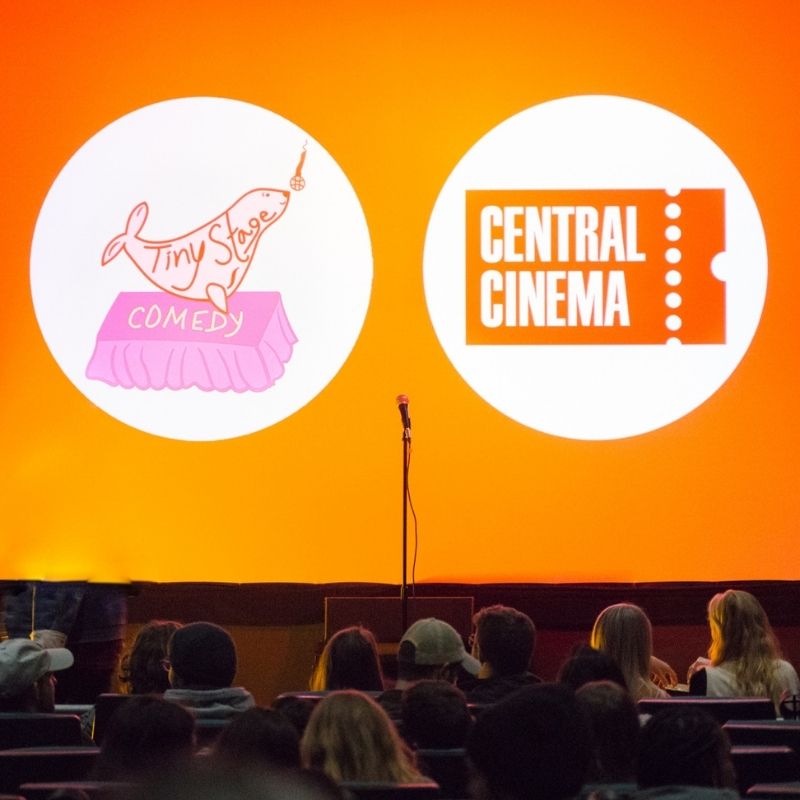 Live comedy show at Central Cinema Knoxville with Tiny Stage Comedy logos on screen